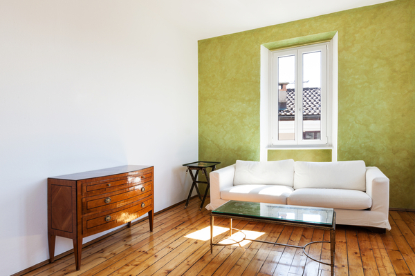 Room with a couch, table, green and white walls and a wood floor