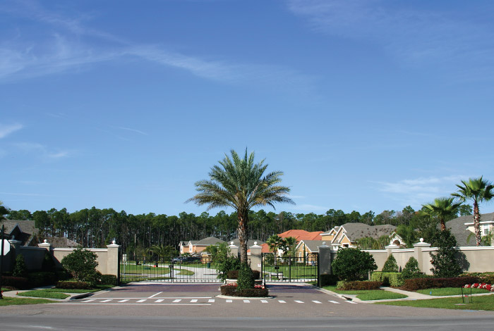 Gate surrounding housing with a palm tree between the exit and enter sides